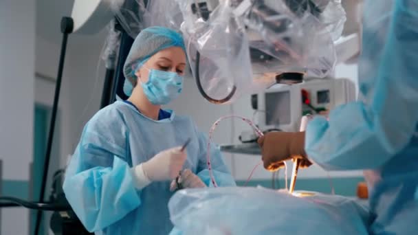 クリニックの近代的な設備を備えたオペレーティング プロセス 手術室で手術中に医療機器を装備した青いユニフォームの外科医とアシスタント — ストック動画