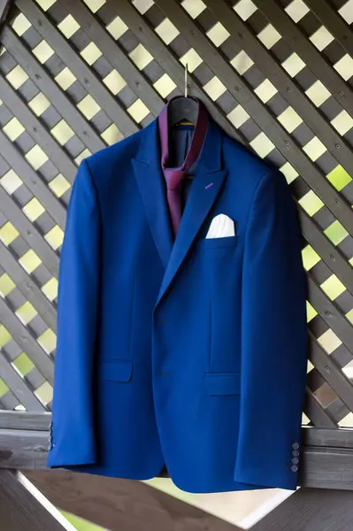 A blue suit hanging on a wooden fence. A Stylish Blue Suit Hanging on a Rustic Wooden Fence