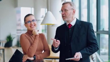 Ofiste gülümseyen meslektaşlar konuşuyor. Genç sekreter kostümü içindeki olgun iş adamını dinliyor ve birlikte eğleniyor..