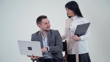 Stüdyoda iş adamı ve çekici sekreter. Laptopuyla oturan yakışıklı adam güzel bir kadınla konuşuyor. Yavaş çekim.