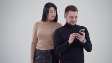 Stüdyoda telefona bakan yakışıklı bir adam. Adamın arkasında duran genç ve güzel bir kadın. Beyaz arka planda genç bir çift.