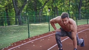 Sakallı sporcu dışarı koşmaya başladı. Kaslı vücutlu üstsüz genç adam yazın stadyumda antrenman yapıyor..