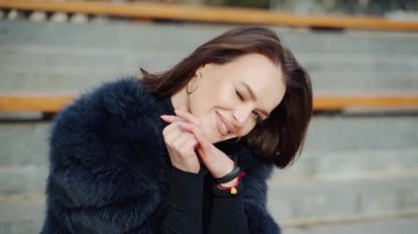 Çekici gülümseyen esmer portresi. Kürklü genç bir kadının güzel yüzü dışarıda oturmuş kameraya bakıyor. Yakın plan..