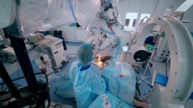Modern ameliyathanede ameliyat süreci. Tıp çalışanları, klinikteki bir hastaya ameliyat sırasında çağdaş ekipman kullanıyorlar. Üst görünüm.