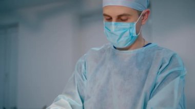 Ameliyat yapan genç bir cerrah. Doktor ve mavi üniformalı bir hemşire klinikteki ameliyathanede ameliyat yapıyorlar..