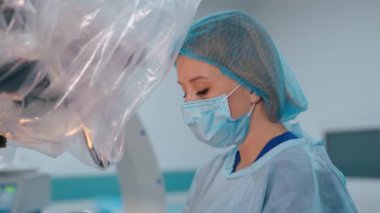 Koruyucu maske takan kadın doktor. Klinikteki ameliyat sırasında kadın asistanın yan görüntüsü. Sağlık hizmetleri kavramı.