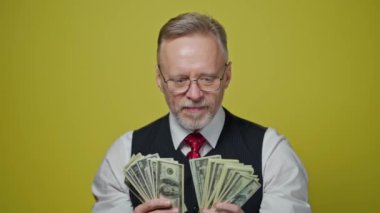 Bir sürü dolar tutan mutlu kıdemli adam. Heyecanlı yaşlı işadamı, sarı stüdyoda tek başına para kazanmaktan zevk alıyor..