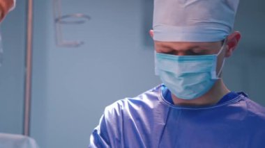 Maskeli profesyonel bir cerrah iş başında. Klinikte doktorlarla birlikte ameliyat yapan bir doktorun portresi..