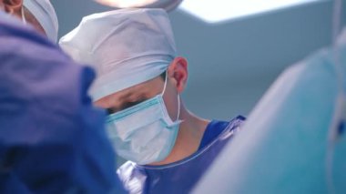 İş yerinde maske takmış bir cerrahın portresi. Modern klinikteki ameliyat sırasında doktorların yüzleri. Yakın çekim. Aşağıdan görüntüle.