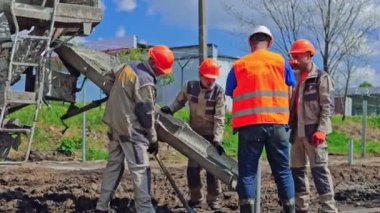 Metal zemin kuran bir grup işçi. Çimentolu endüstriyel makine. İşçiler yere güneş panelleri yerleştirmeden önce metal yapı döşedi.