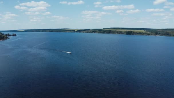 自然の中で広い青い川のパノラマビュー 夏に川の真ん中に浮かぶモーターボート エアリアルビュー — ストック動画