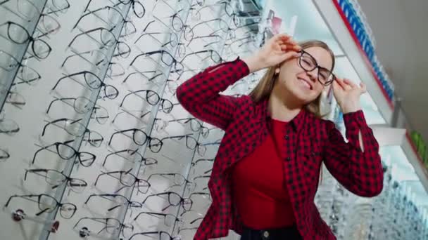 Улыбающаяся Девушка Покупает Очки Магазине Привлекательная Молодая Женщина Примеряет Новые — стоковое видео