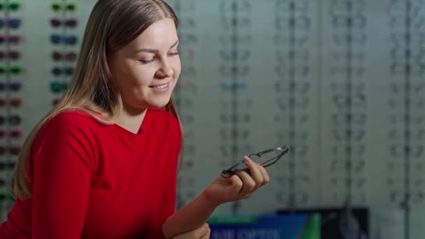 Retrato Uma Jovem Mulher Loja Óptica Mulher Sorridente Detém Óculos — Vídeo de Stock
