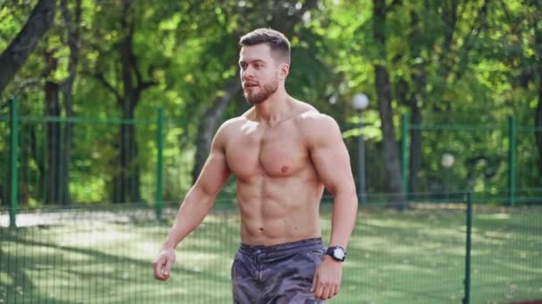 室外体育场上的肌肉男跑步者 一个没有衬衫的强壮运动员的画像准备在跑道上跑步 慢动作 — 图库视频影像