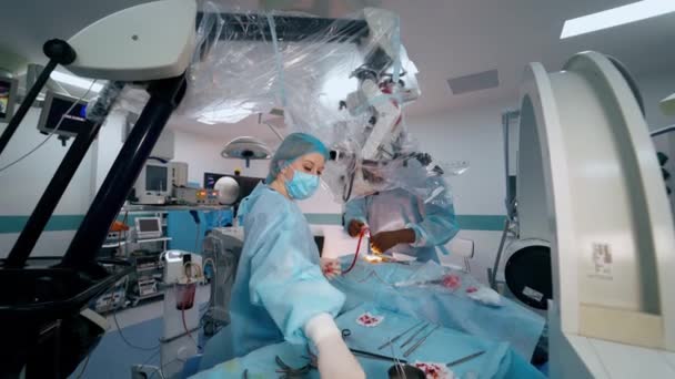 手術における革新的な技術 外科医が手術をする 手術室で医師の医療機器を提供する女性アシスタント — ストック動画