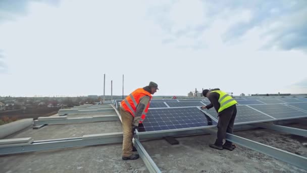 Instalasi Baterai Cerah Atap Dua Pekerja Berseragam Memasang Panel Fotovoltaik — Stok Video