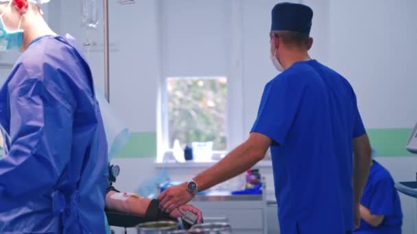 Kirurgiskt Ingrepp Operationssalen Manlig Läkare Kontrollerar Patientens Puls Operationen Kliniken — Stockvideo