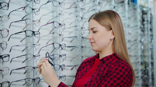 光学商店的女顾客 漂亮的年轻女子在商店里选择新的时髦眼镜 眼镜的概念 — 图库视频影像