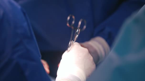 外科医は医療機器で手袋をしています 医師団が患者を動かしている 手術中に医学的なハサミで血液中の手 クローズアップ — ストック動画