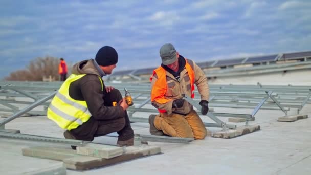 Pracuje Przy Budowie Paneli Słonecznych Dwóch Robotników Instalujących Metalową Podstawę — Wideo stockowe