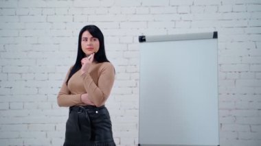 Düşünceli bir iş kadınının portresi. Tahtanın yanında duran genç ve güzel bir bayan yeni iş yolları düşünüyor..
