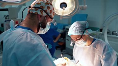 Cerrah ve asistanı hastane ameliyathanesinde estetik ameliyat yapıyorlar. Tıbbi prosedür sırasında maske takan cerrah..