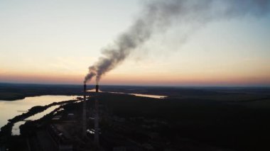Günbatımı arka planında fabrika tüpleri. Borulardan duman çıkıyor. Kirlilik konsepti. Havadan video.