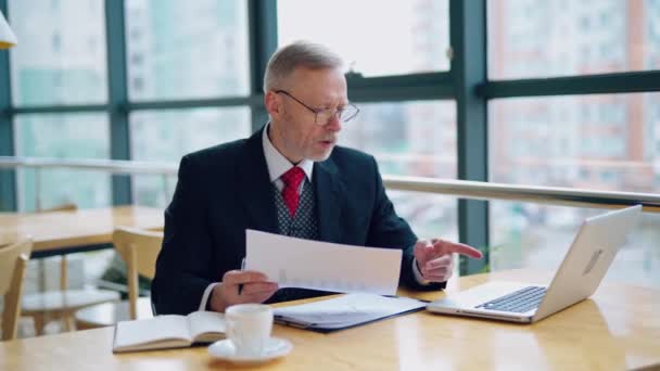 Бизнесмен Проверяет Распечатанный Отчет Документ Сидя Столом Работая Над Бумажной — стоковое видео