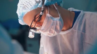 Cerrahi maskeli bir kadın doktor portresi. Estetik ameliyat yaparken aşağı bakan profesyonel bir uzman. Yakın plan..