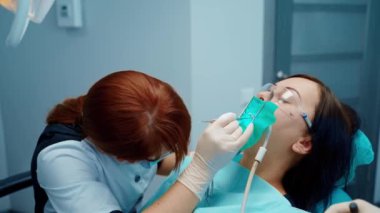 Dişçilikte stomatoloji tedavisi. Stomatolog hastanın dişlerini tedavi ediyor. Dişçi modern stomatoloji kliniğinde genç bir kadının dişlerini tedavi ediyor..