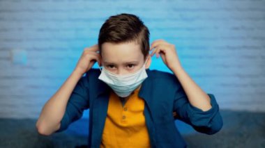 Virüslerden, salgınlardan, hava kirliliğinden ve tehlikeli parçacıklardan korunmak için tıbbi maske takan genç bir çocuk. Koronavirüsü durdurun..