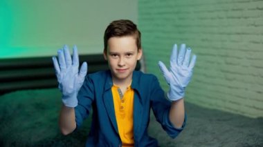 Çocuk tıbbi lastik eldiven giyiyor. Çocuk kameranın önünde lastik eldivenlerle el ele tutuşuyor. Koronavirüsü durdurun. Salgın. COVID-19