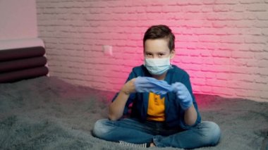 Tıbbi maske ve eldiven takan çocuk. Evde kendini izole et. Koronavirüs salgını ve sosyal uzaklık kavramı. Sakin ol ve evde kal..