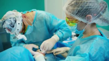 Klinikte estetik ameliyat. Ameliyat sırasında tıbbi aletlerle çalışan profesyonel bir doktor. Kadın hemşire ameliyathanede cerraha yardım ediyor..