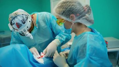 Doktor ve hemşire estetik ameliyat yapıyor. Maskeli tıp uzmanları ameliyathanede ameliyat yapıyor..