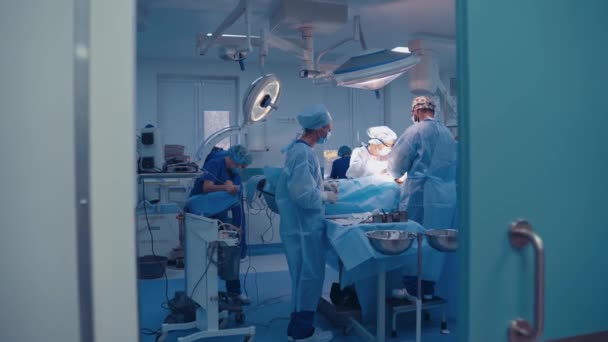 現代の診療所で手術を行っている外科医のチーム 青い制服の医療従事者のグループは 患者に手術を行います — ストック動画