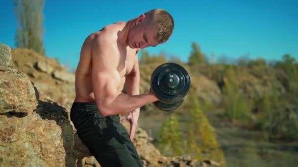 Muskelmannen Lyfter Metallhanteln Naturen Shirtless Idrottsman Tränar Axelmusklerna Nära Berget — Stockvideo