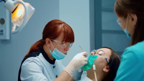 牙科医生注意治疗病人的牙齿 口腔科诊所的口腔卫生程序 女口腔科医生和一名治疗女童牙齿的护士 — 图库视频影像