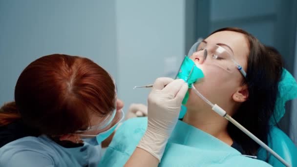 Kvinnan Stolen Stomatologiska Kliniken Professionell Kvinnlig Tandläkare Skyddsmask Och Glasögon — Stockvideo