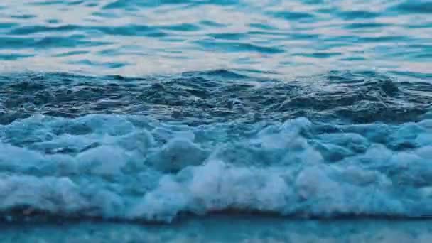 海水の背景 海岸で泡立った波が飛び交う 青い海水の息をのむような景色 クローズアップ スローモーション — ストック動画