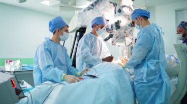 Profesyonel cerrahlar modern tıbbi ekipman kullanır. Bir grup doktor hastanede mikroskopla bir beyin cerrahisi yapıyor..