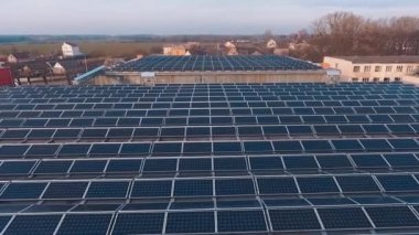 Yenilikçi güneş enerjisi santrali çatıda. Kırsal kesimdeki devasa sanayi binalarının çatılarında birçok güneş paneli var. Güneş çiftliğinin kurulumu. Hareket kamerası geri..