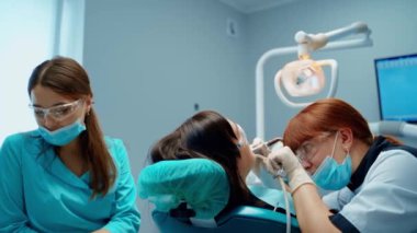 Bayan müvekkil çürükler için tedavi görüyor. Diş hekimi modern stomatoloji ofisinde dişlerini diş makinesiyle tedavi ediyor..