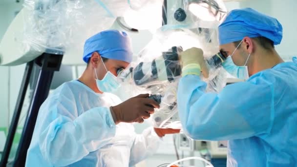 Idegsebészet High Tech Felszereléssel Két Férfi Sebész Akik Orvosi Mikroszkóppal — Stock videók