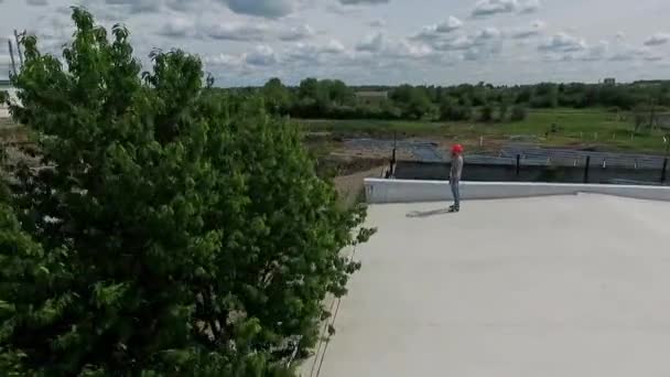 Technik Pomarańczowym Twardym Kapeluszu Dachu Latem Instalator Patrzący Budowę Farmy — Wideo stockowe