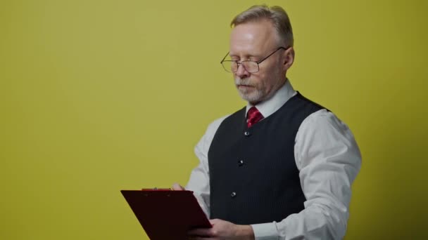 폴더가있는 심각한 남자의 초상화 폴더에 안경을 노인은 노란색 배경에 감정을 — 비디오