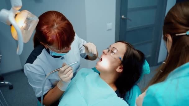 若い女性がストロマトロジーキャビネットを訪れます 歯科クリニックで少女の歯を治療する無菌手袋の歯科医師 歯科コンセプト — ストック動画