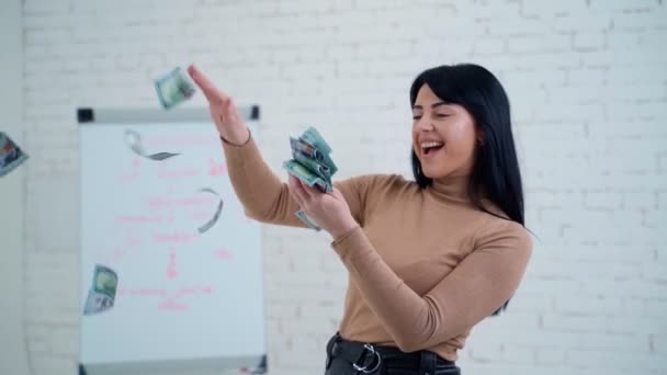 ドル紙幣を持った幸せなビジネス女性 笑顔の若い女性が勉強室でお金を投げている 成功した少女がお金を散らす — ストック動画