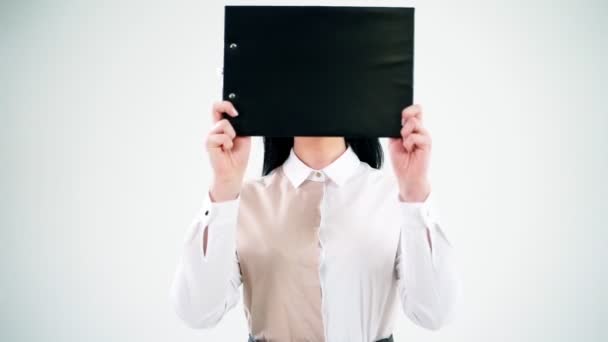 有黑色文件夹的女商人迷人而快乐的年轻女人把脸藏在文件夹里 微笑的秘书一个人站在办公室里 积极的情绪 — 图库视频影像