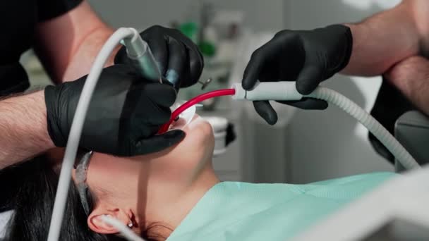 牙医手戴黑色手套 治疗妇女的牙齿 胃科医生和助手使用现代方法治疗病人的牙齿 后续行动 — 图库视频影像